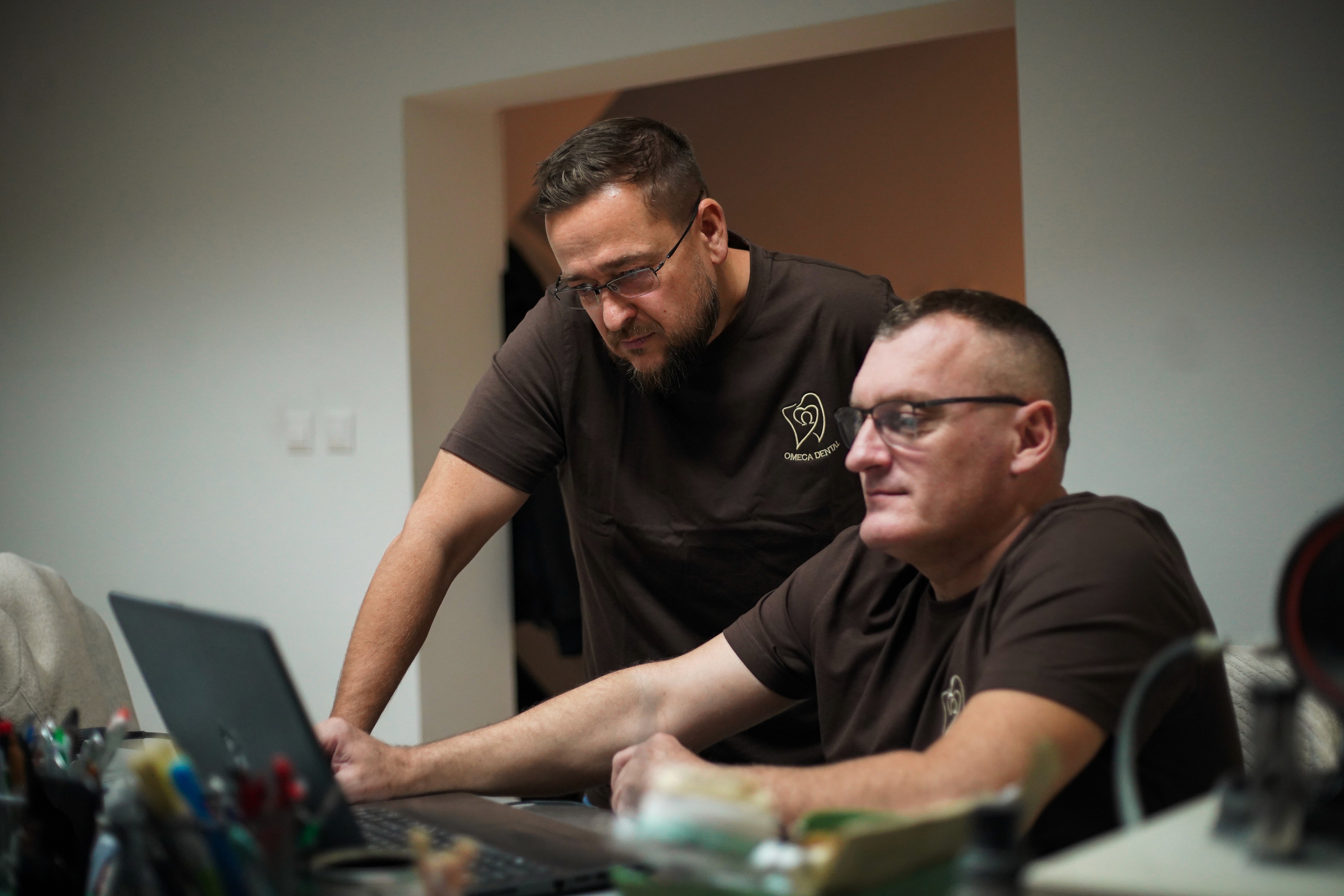 Dvaja technici Omega Dental spolupracujú na zubnom prípade pri pracovnom stole