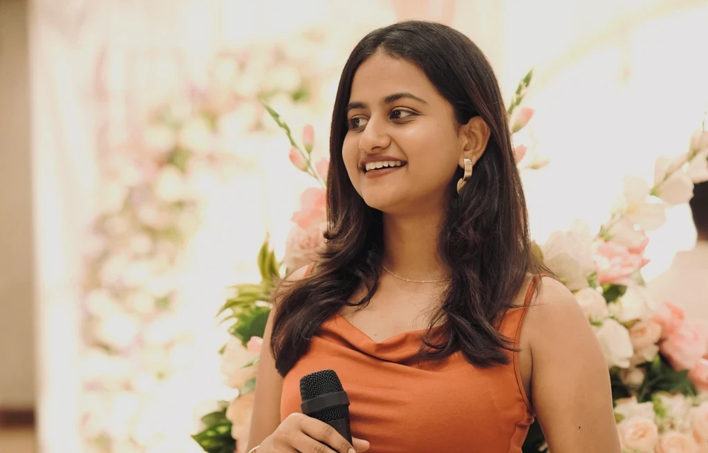 Women holding a microphone and smiling in an event.