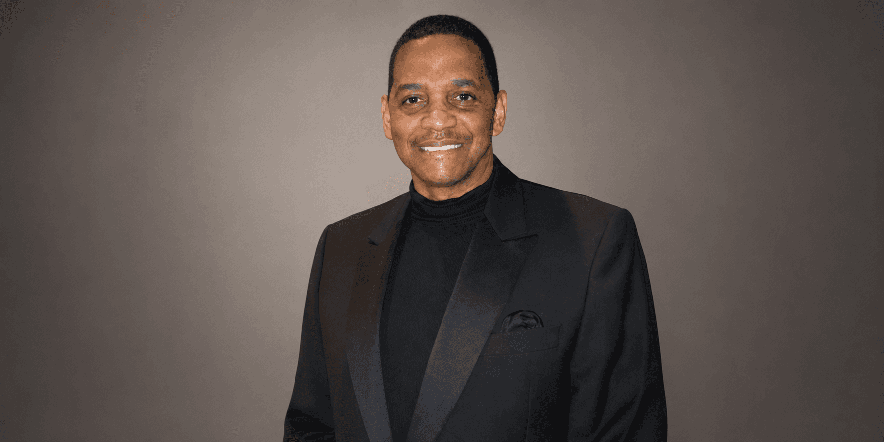Prof. Robert Stewart Ph.D. wearing a black suit against a gray background.
