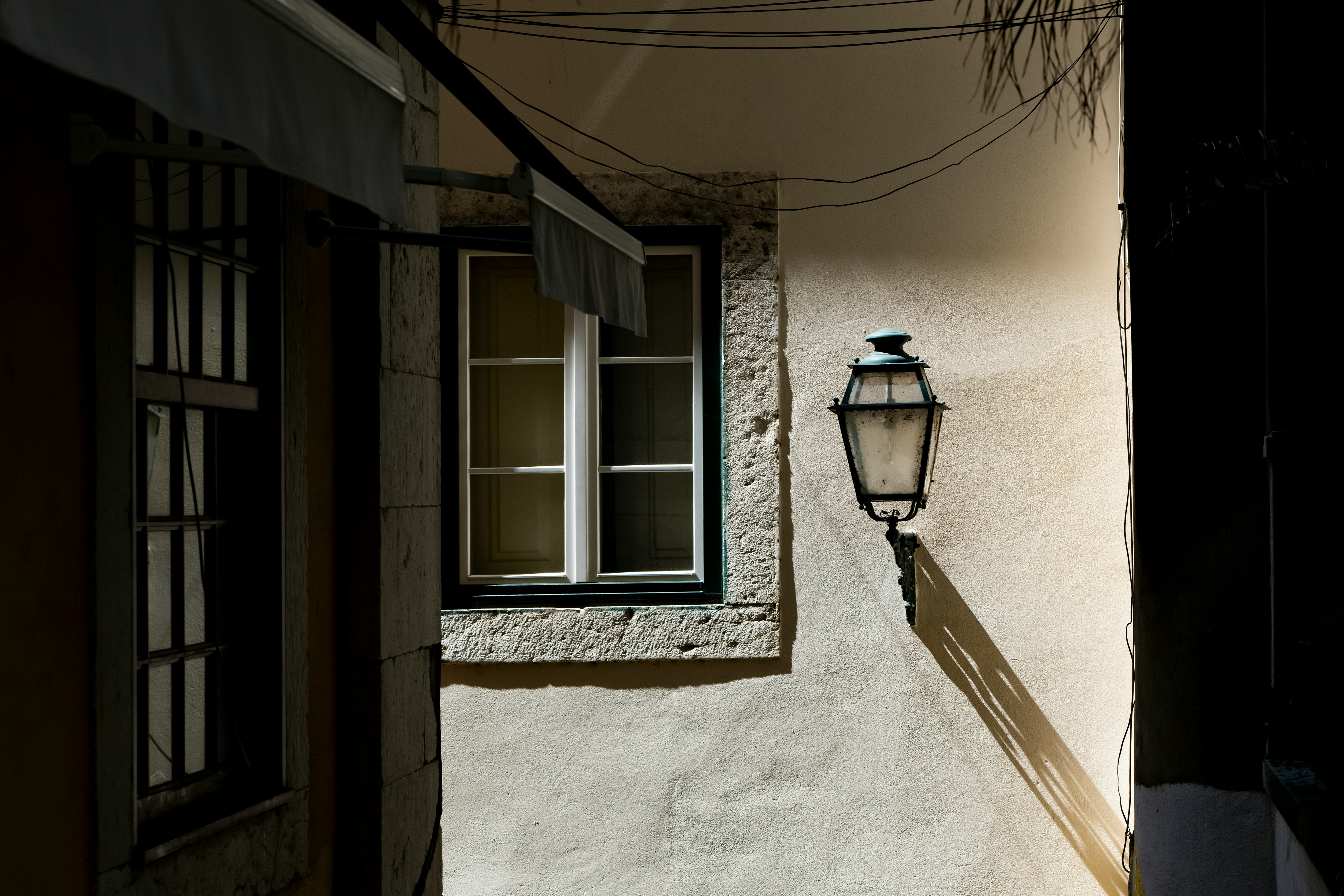 A traditional white-themed wall with a window and a lamp placed on the right.