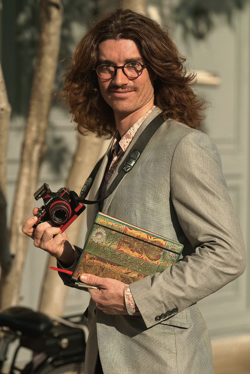 Martin Dedron, un professionnel de la création tenant son appareil photo et son calepin