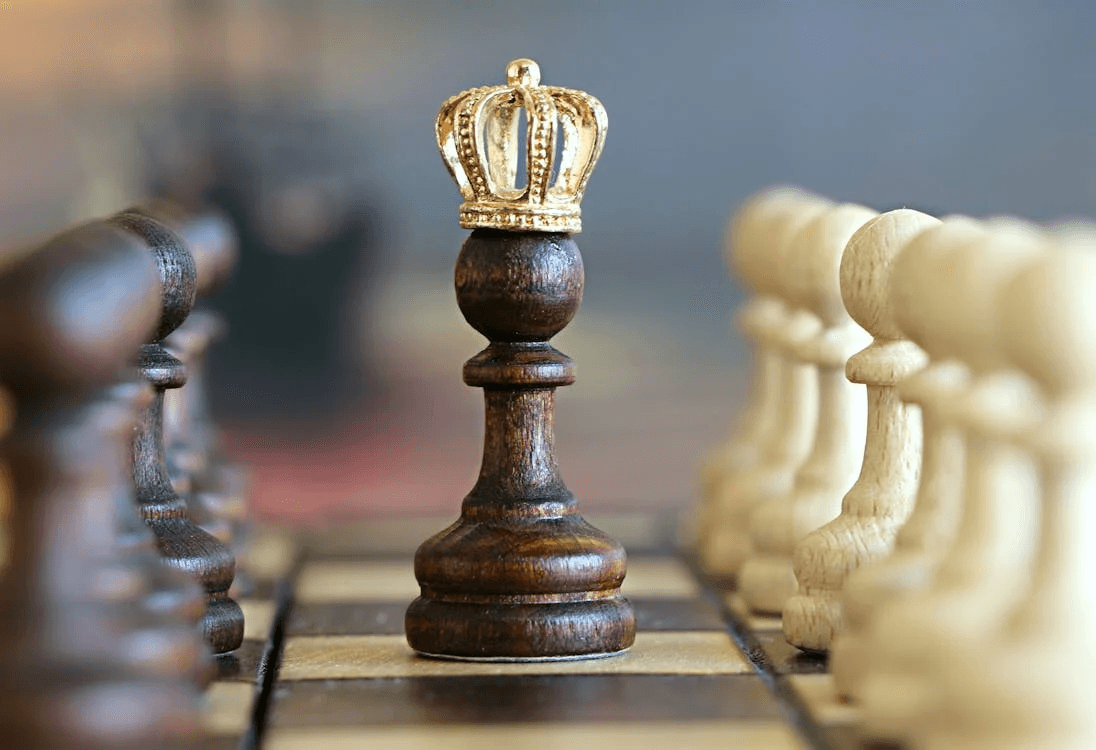 Close up Image of a pawn in the middle of the chess board wearing a golden crown