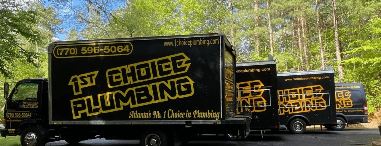 Fleet of 1st Choice Plumbing service trucks parked in front of trees