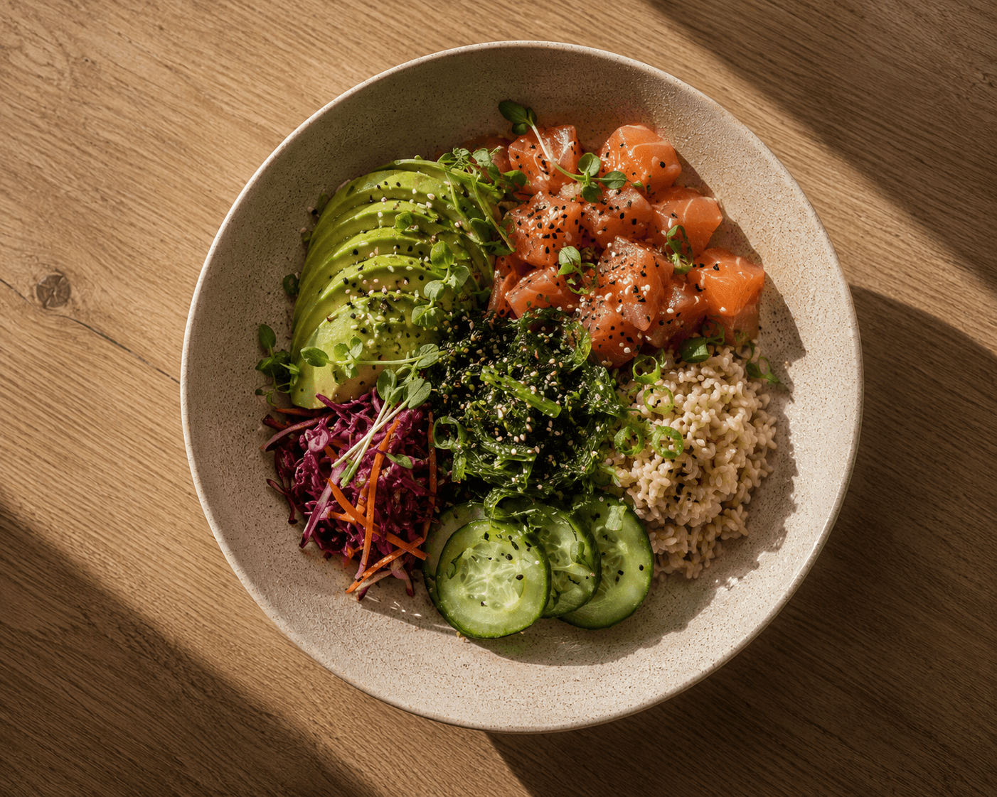 Salmon poke bowl with avocado, brown rice, cucumber, pickled red cabbage, kale and sesame seeds