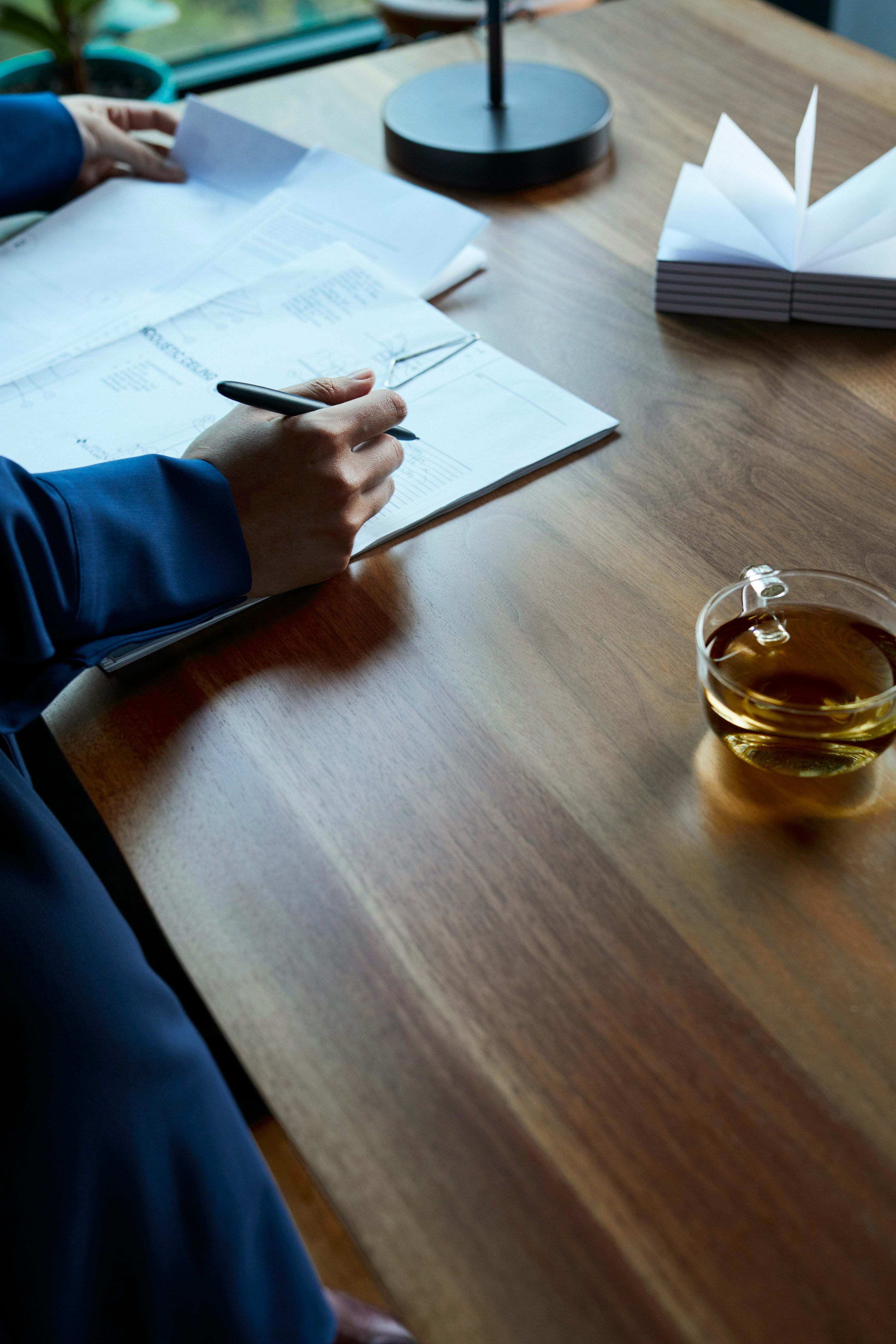a person sitting at a table writing on a piece of paper