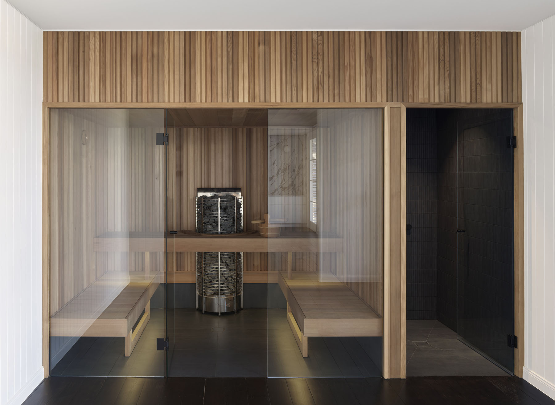 timber-lined sauna interior with glass enclosure and central heater