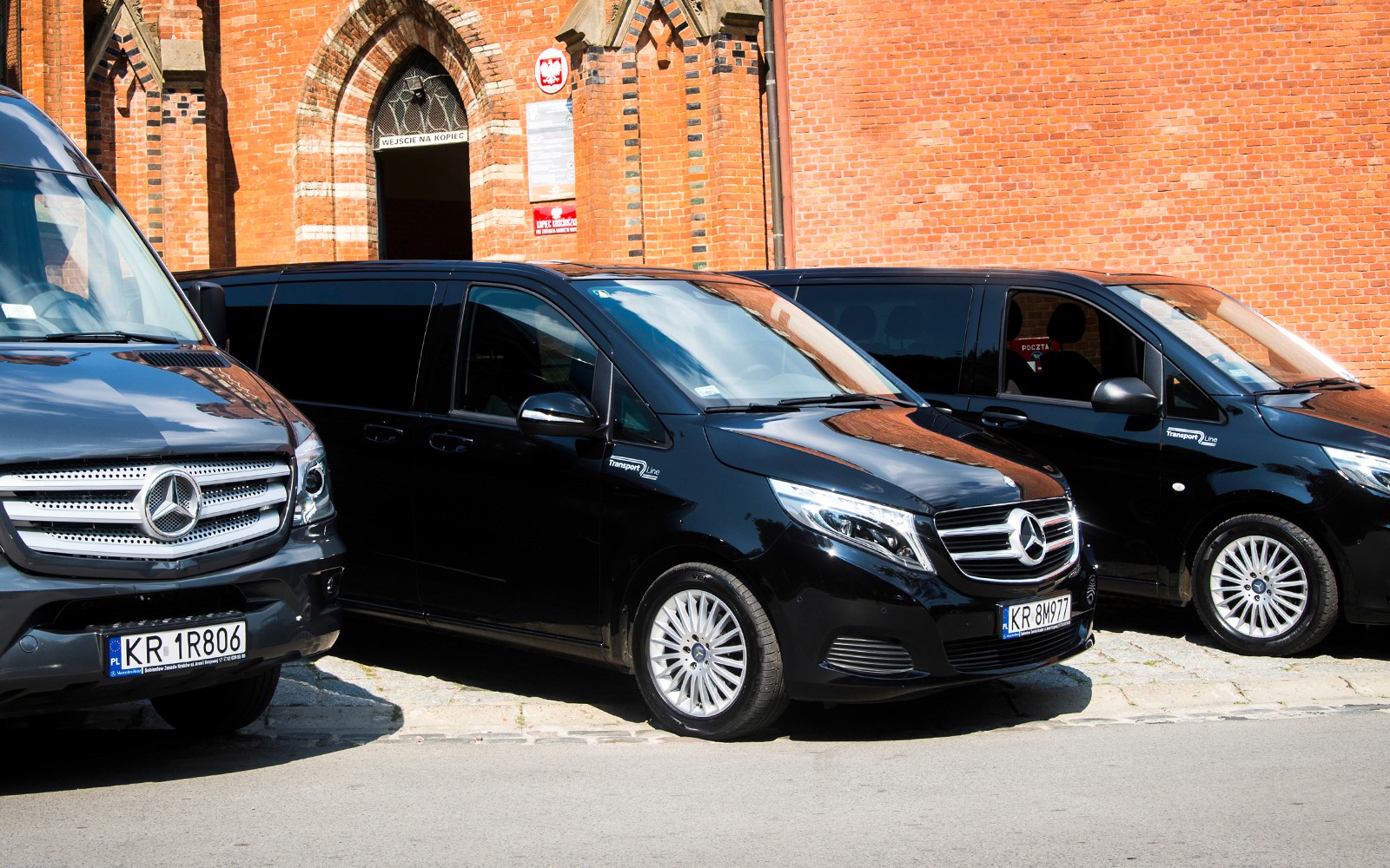 Furgoni Mercedes parcheggiati fuori da un edificio in mattoni per il trasferimento all'Aeroporto di Cracovia-Balice.