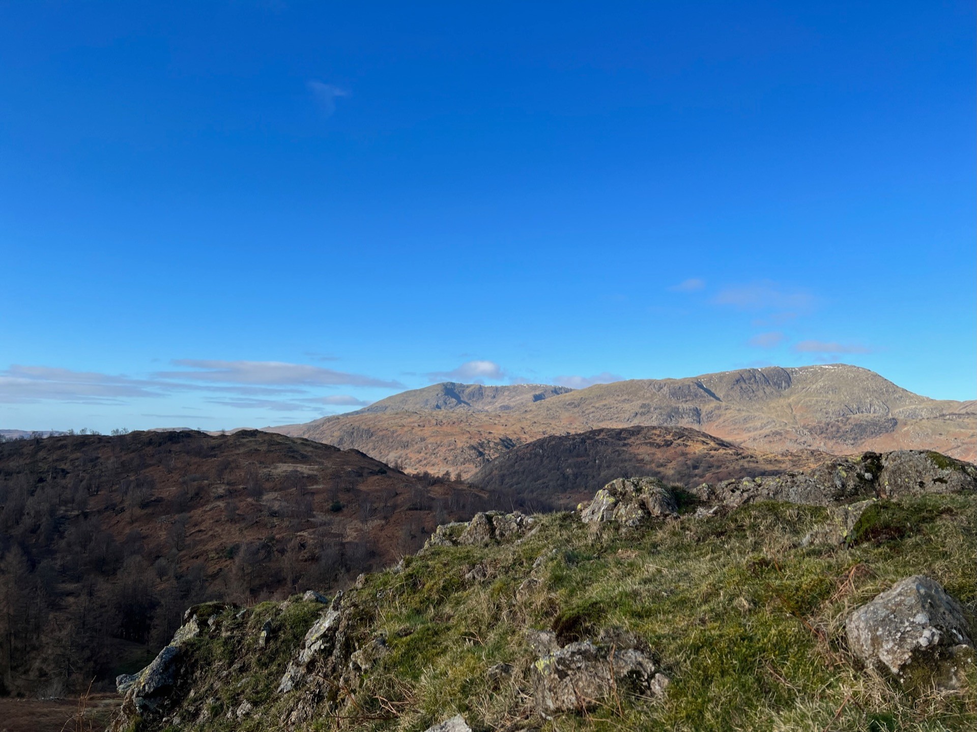 Mountain views and a clear blue sky. A rocky crag in the foreground.