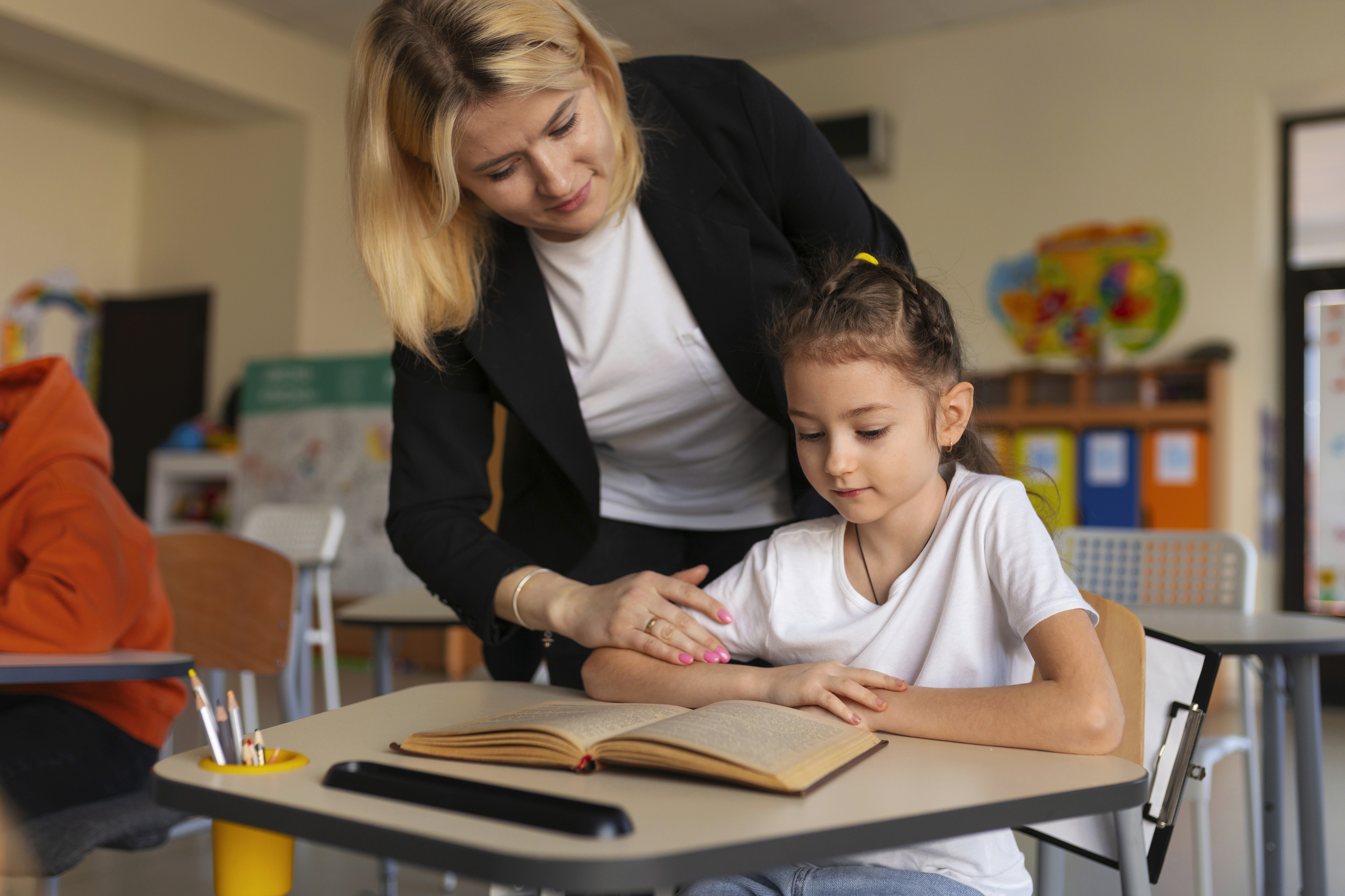 Teacher helping a student. Image by Freepik.