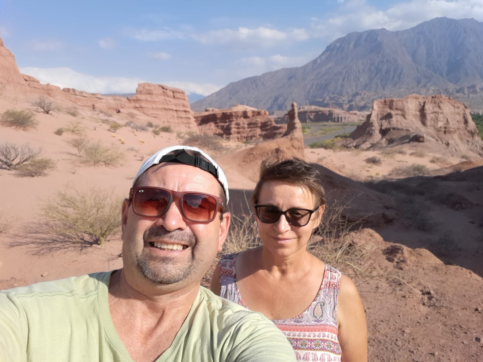 Mujer sentada sobre un tronco frente a una cascada doble en un bosque frondoso de Argentina.