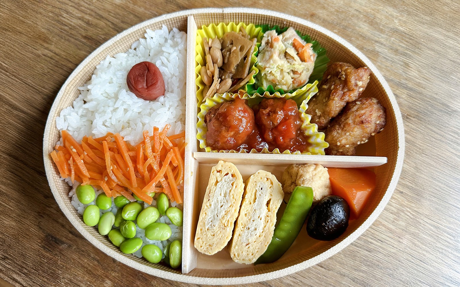 Traditional Japanese bento with rice, pickled plum, vegetables, and assorted side dishes.