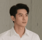 A young man with dark hair and a serious expression, wearing a white shirt against a neutral background.