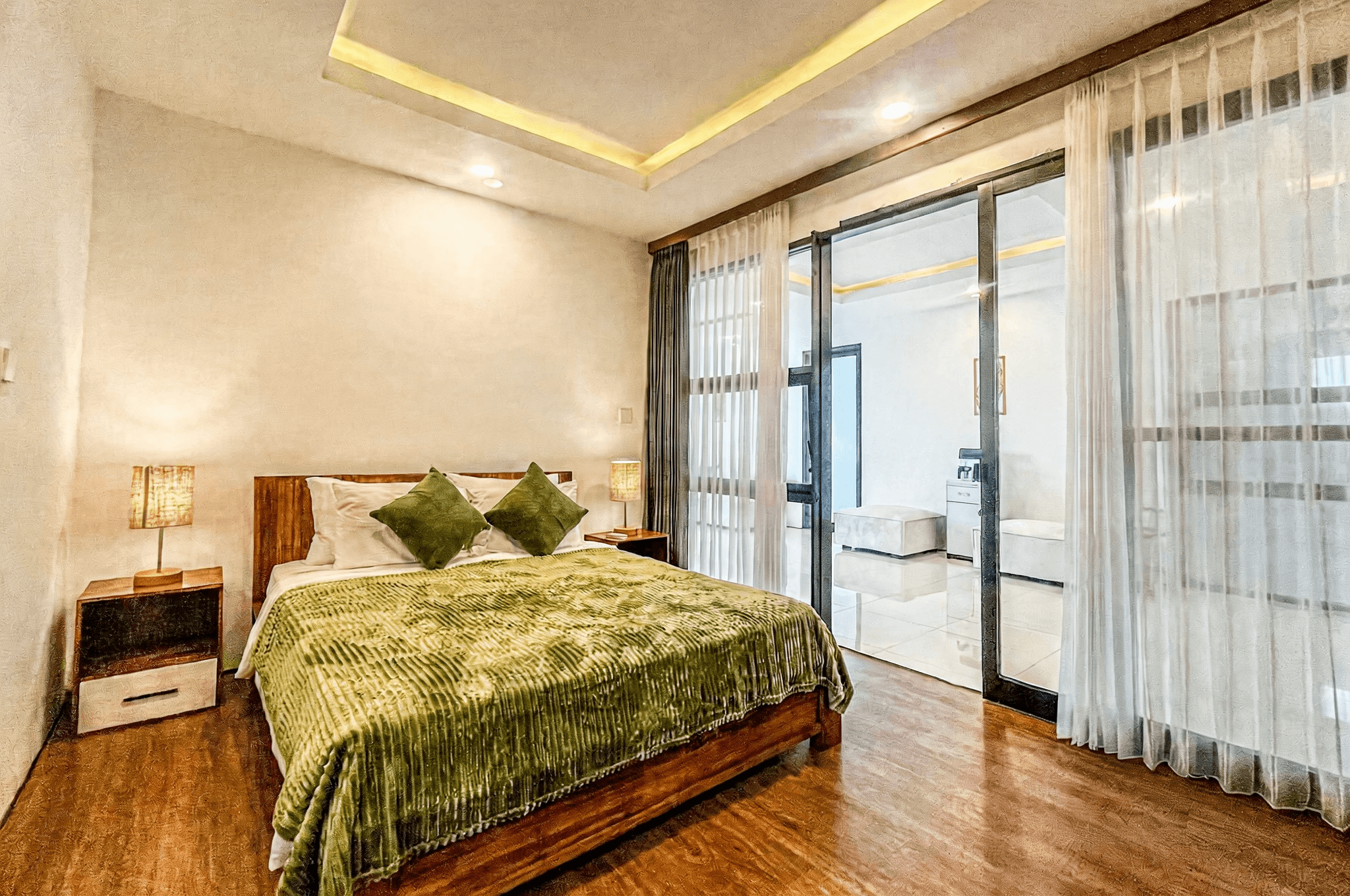 Minimalist master bedroom at Ungasan I with warm lighting and wooden flooring for a luxury Bali lifestyle.