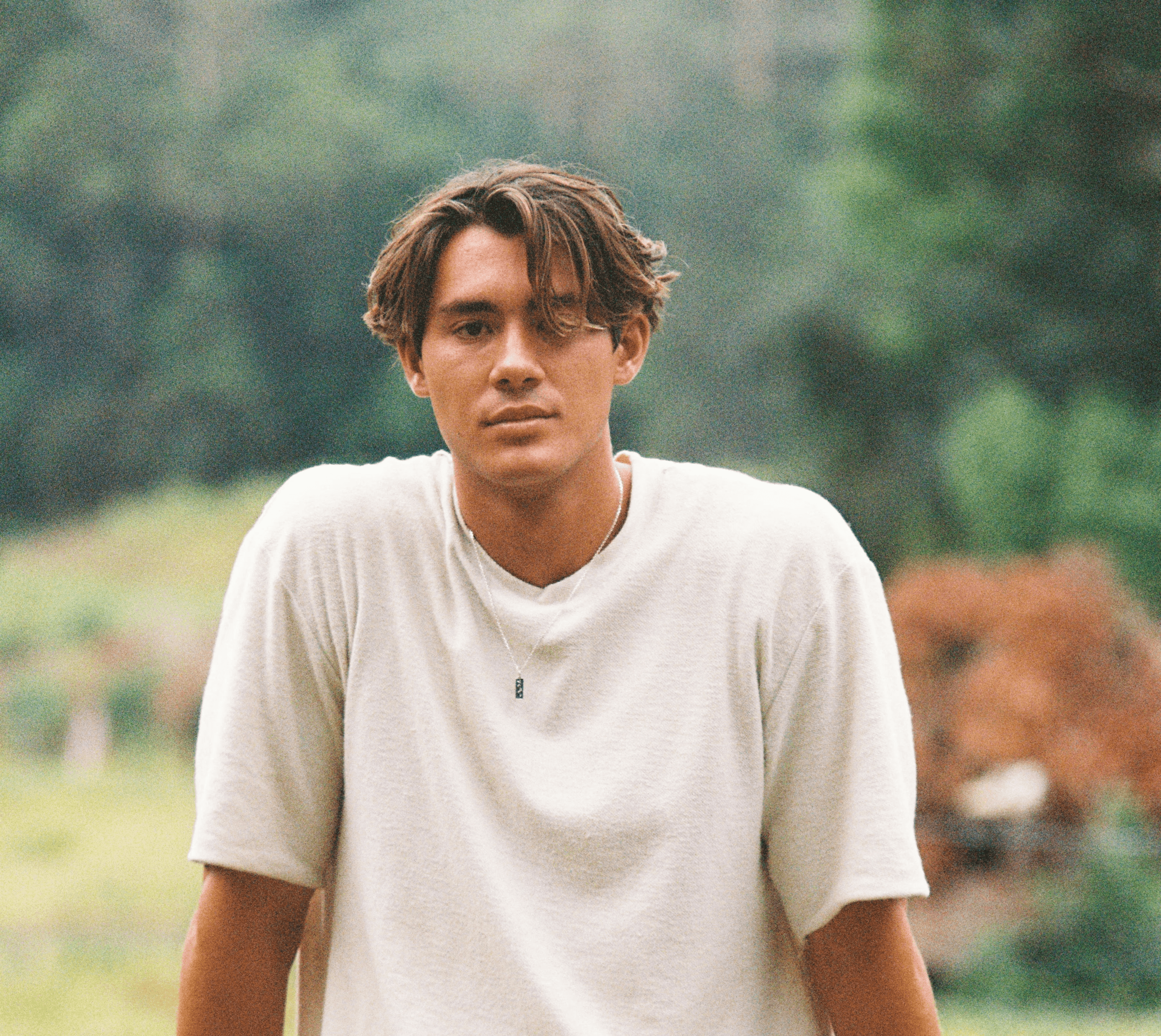man in white crew neck t-shirt and black pants sitting on rock during daytime