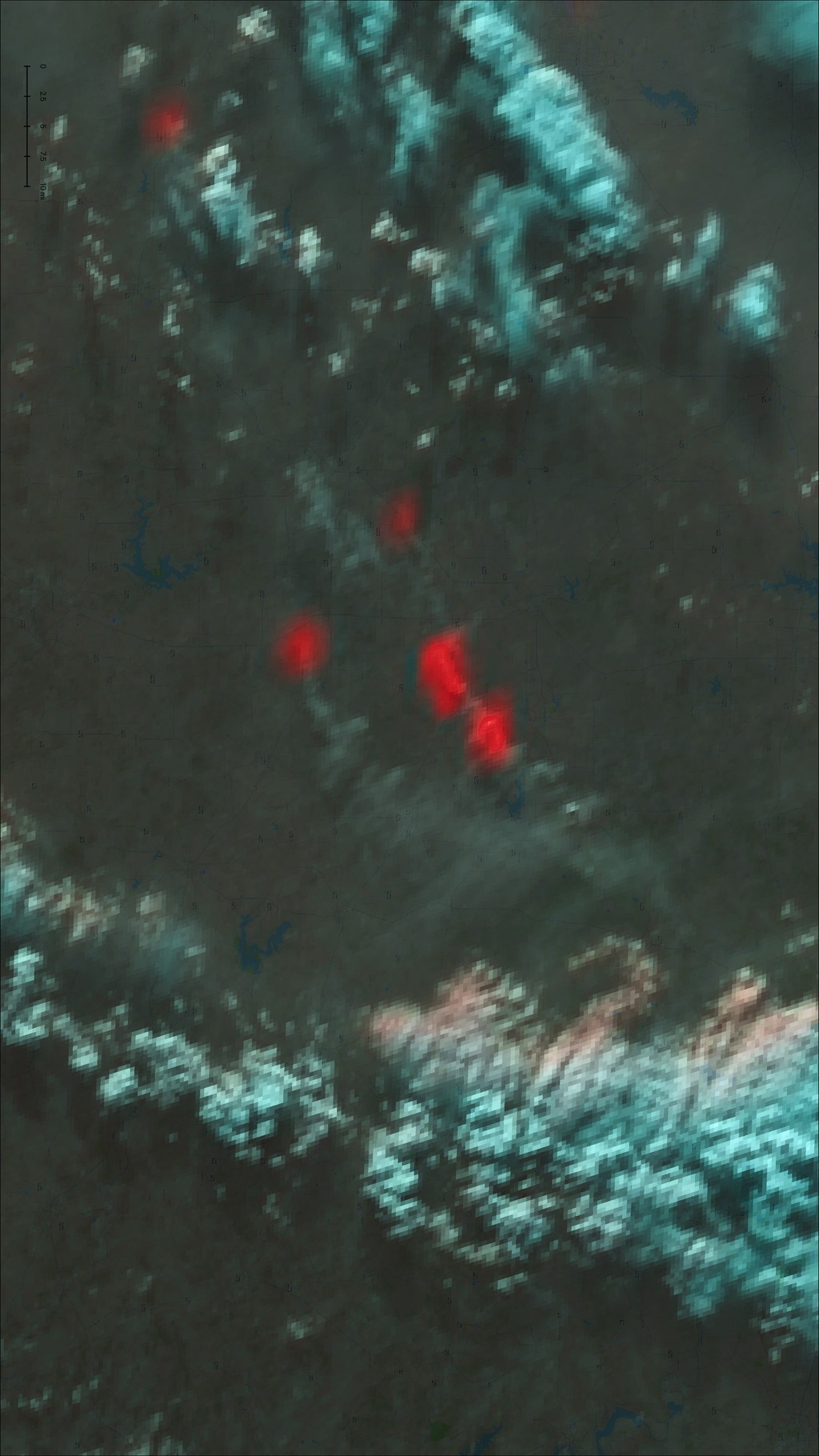 Satellite image displaying a dark landscape with bright red patches indicating areas of volcanic activity or thermal hotspots against a backdrop of blue and gray hues.
