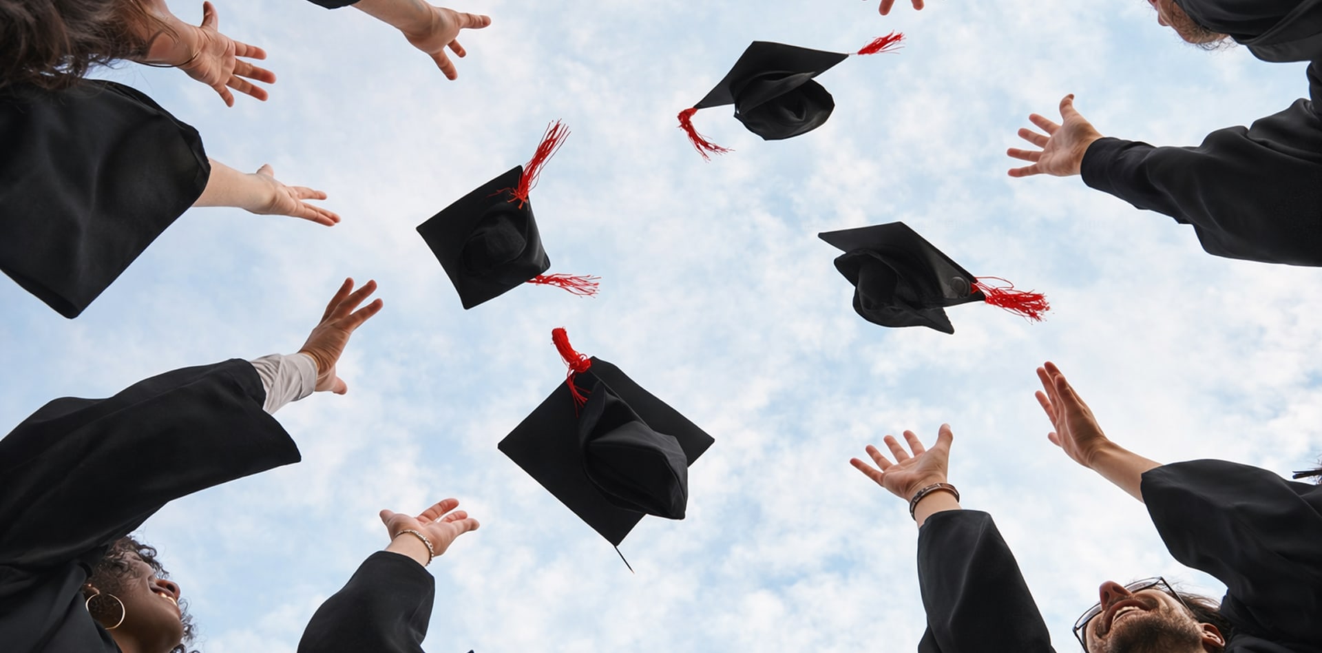 Gruppo di laureati lancia i cappelli in aria, celebrando insieme un momento di traguardo e condivisione.