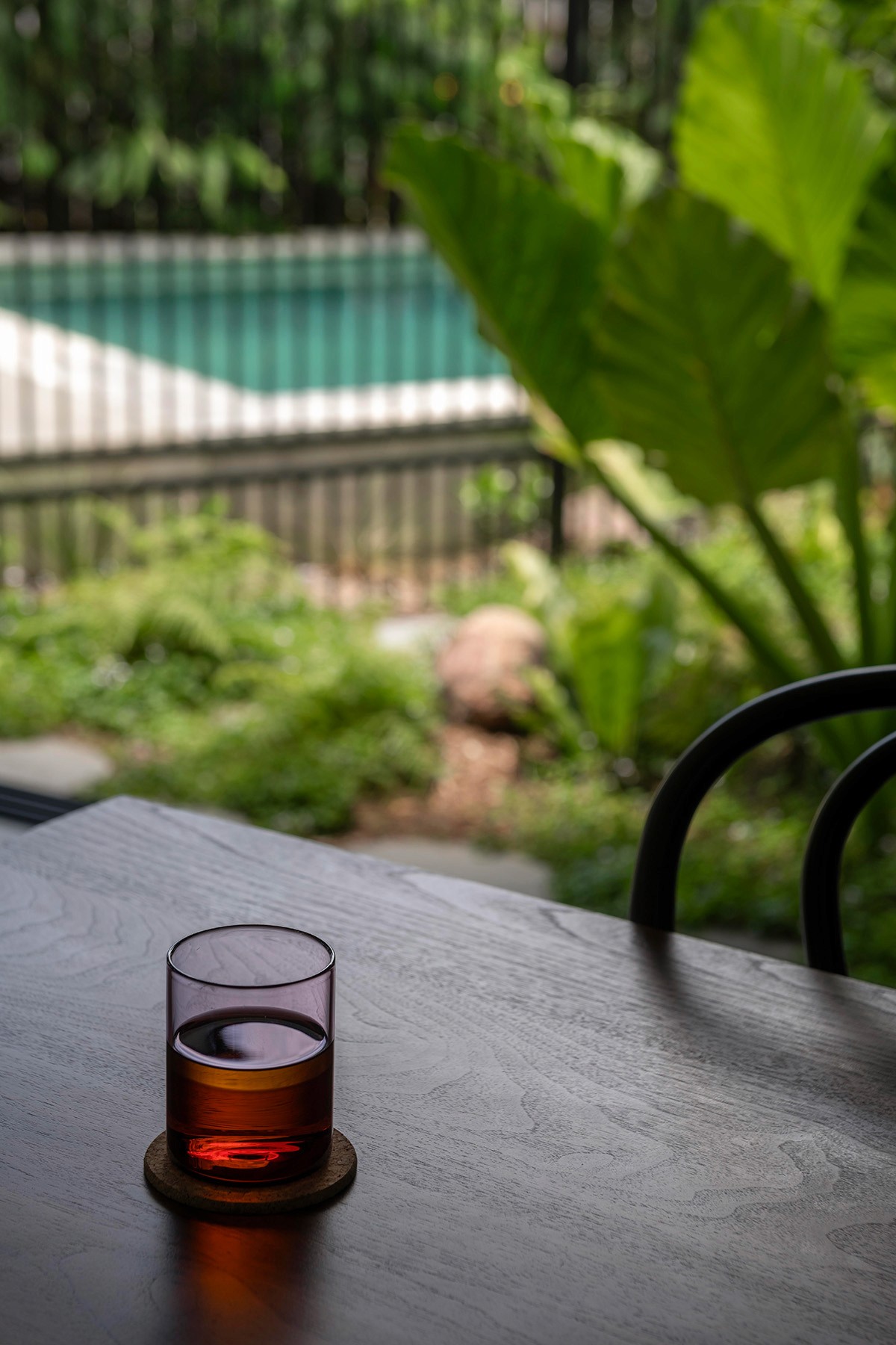 Interior detail of Toohey Forest House showing timber table with glass and views to landscaped garden courtyard.