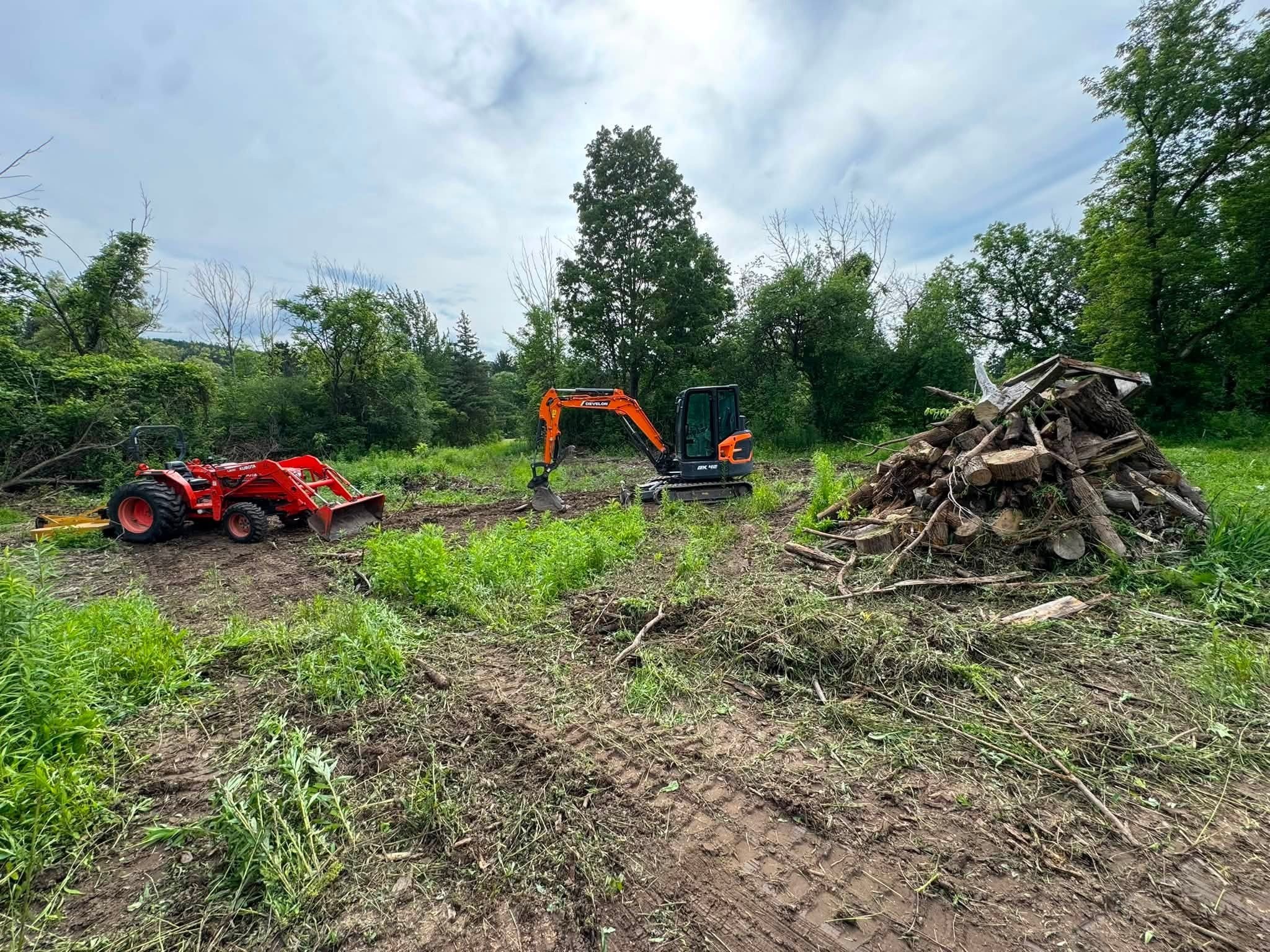 Tractor and mini excavator clearing brush and stacking debris on an overgrown property