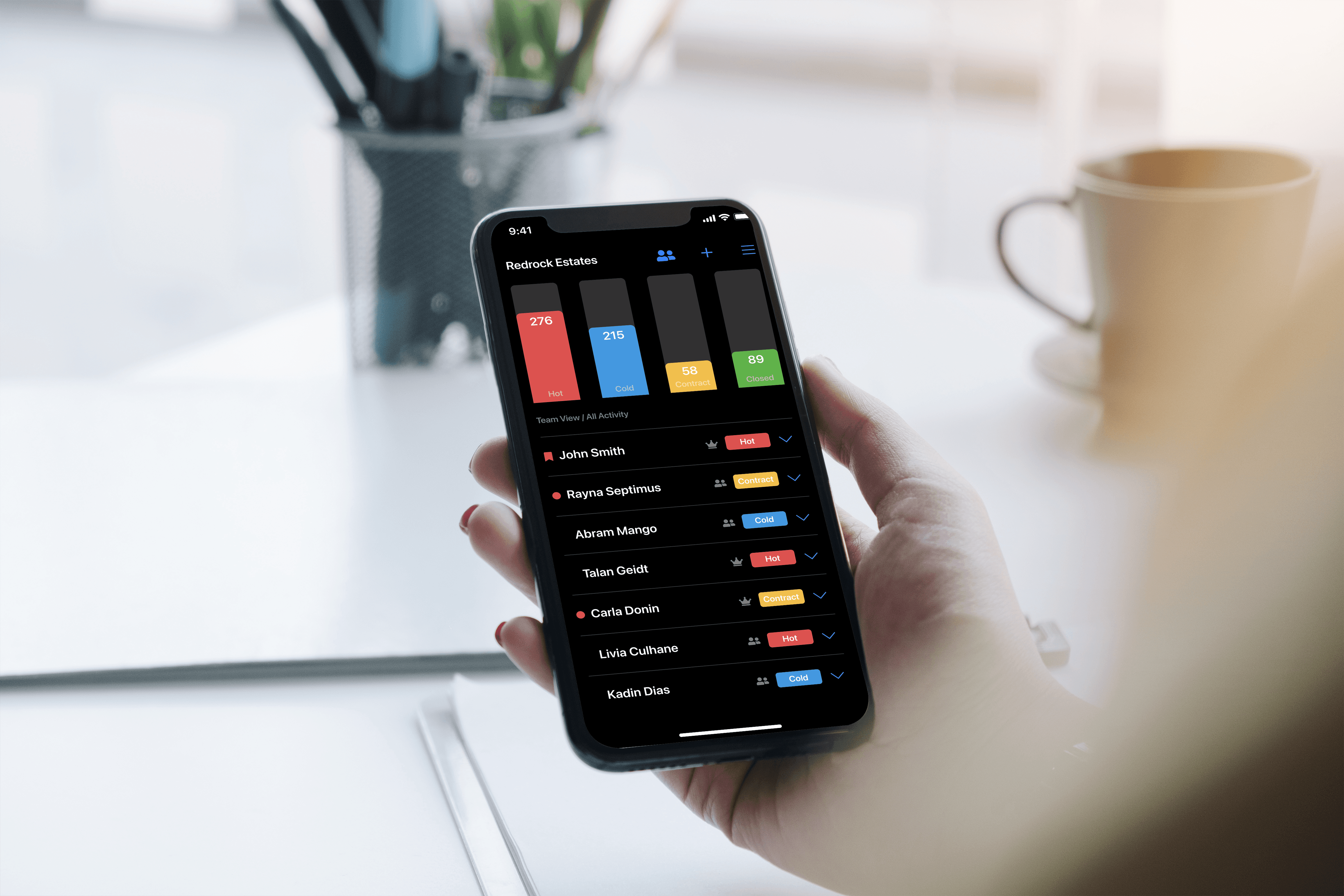 Hand holding a phone showing the NoviHome Focus app dashboard