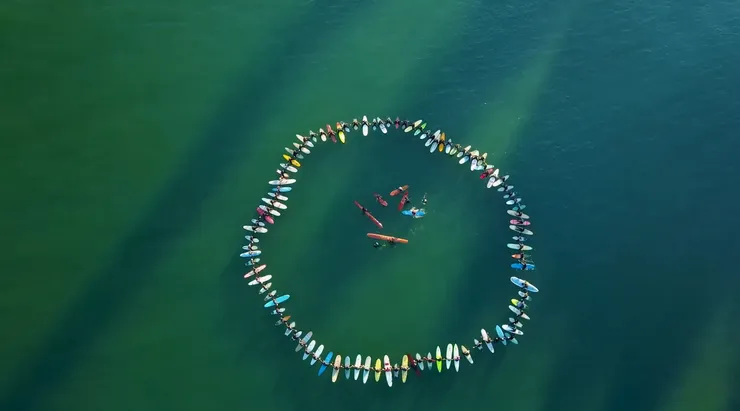 A smiling young man with crossed arms, wearing a plaid shirt and white t-shirt, poses against a dark background.