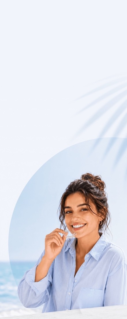 Smiling girl in blue shirt inserting Invisalign clear aligners, enjoy the summer offer now at Invisalign Center Dubai.