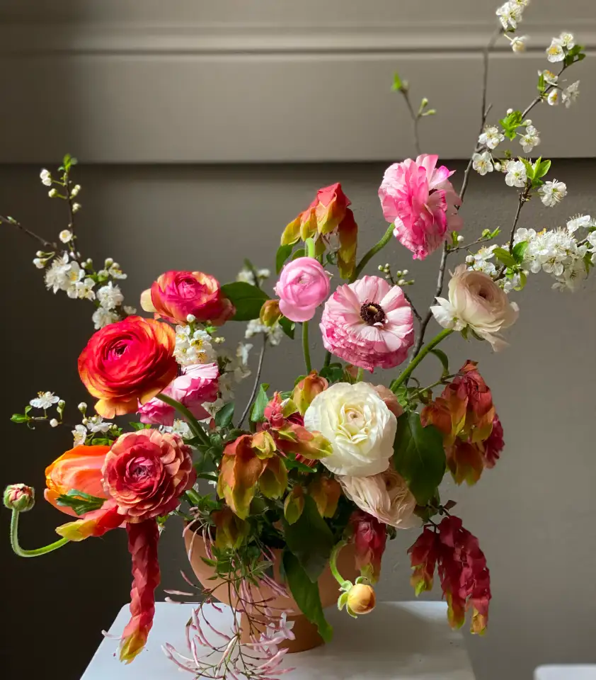 Arreglo floral contemporáneo con ranúnculos y flores de estación, composición orgánica con movimiento y color.