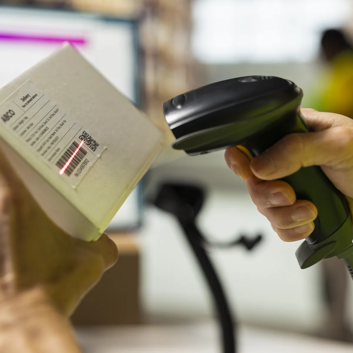 Close-up of a handheld scanner reading the barcode on a parcel label