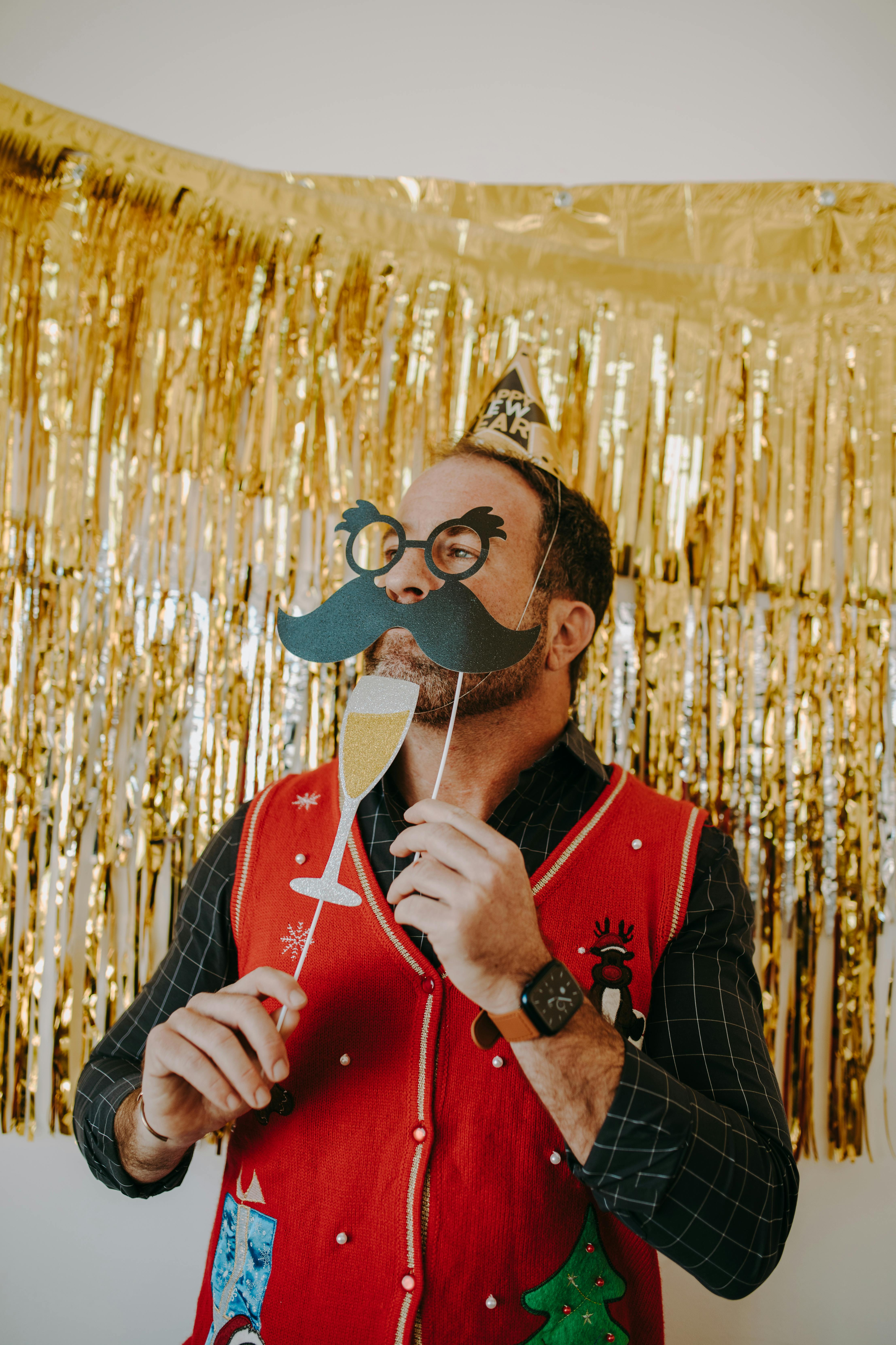 man-in-festive-attire-holding-paper-props-at-a-celebration-with-gold-decor. - rdne-stock-project (pexels)