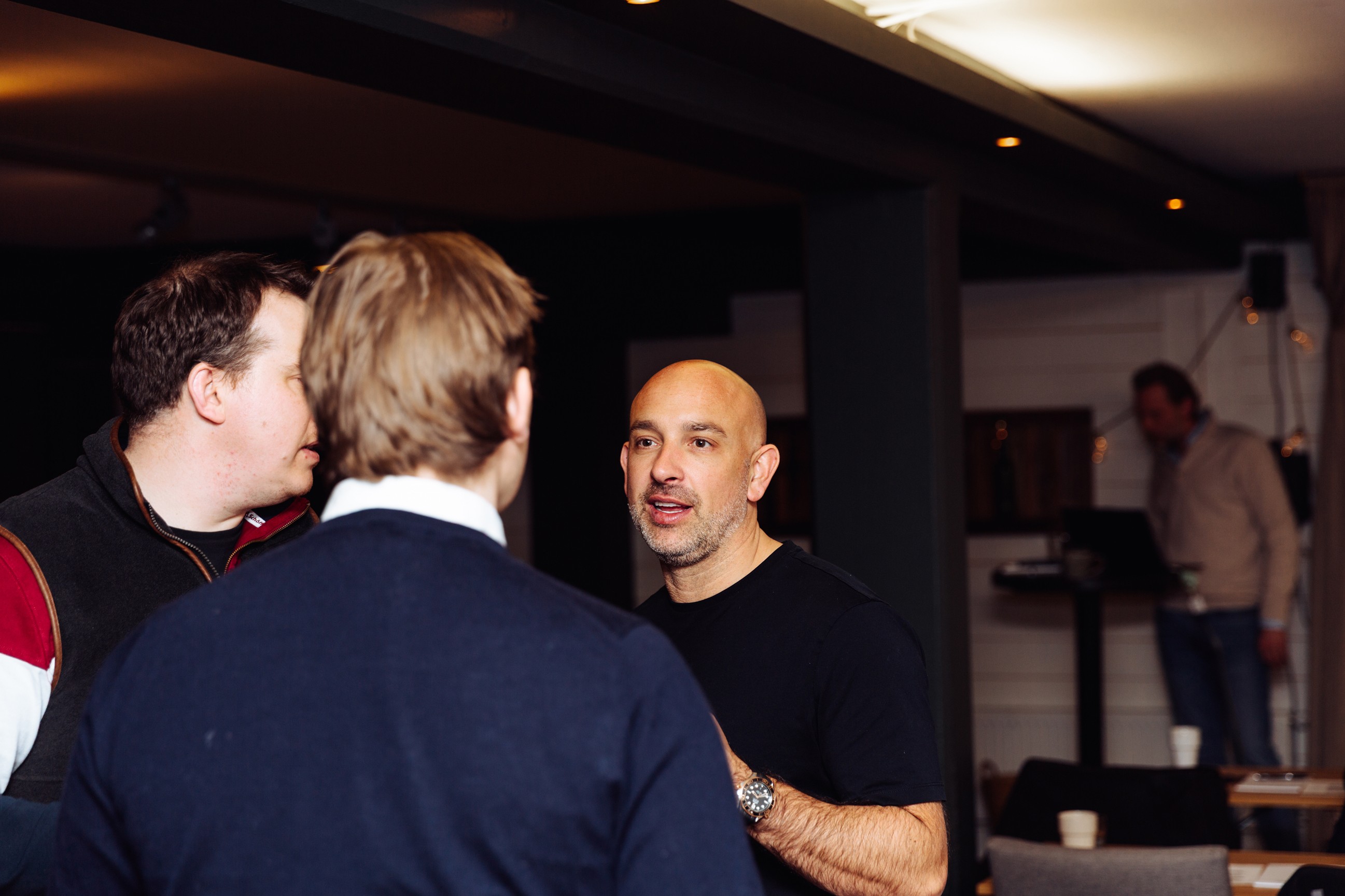 a group of people sitting around a table with laptops