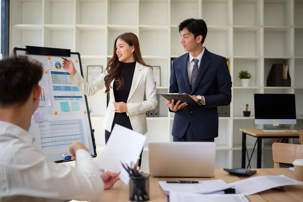 Business leaders collaborating over a healthcare analytics dashboard to improve workforce well-being.