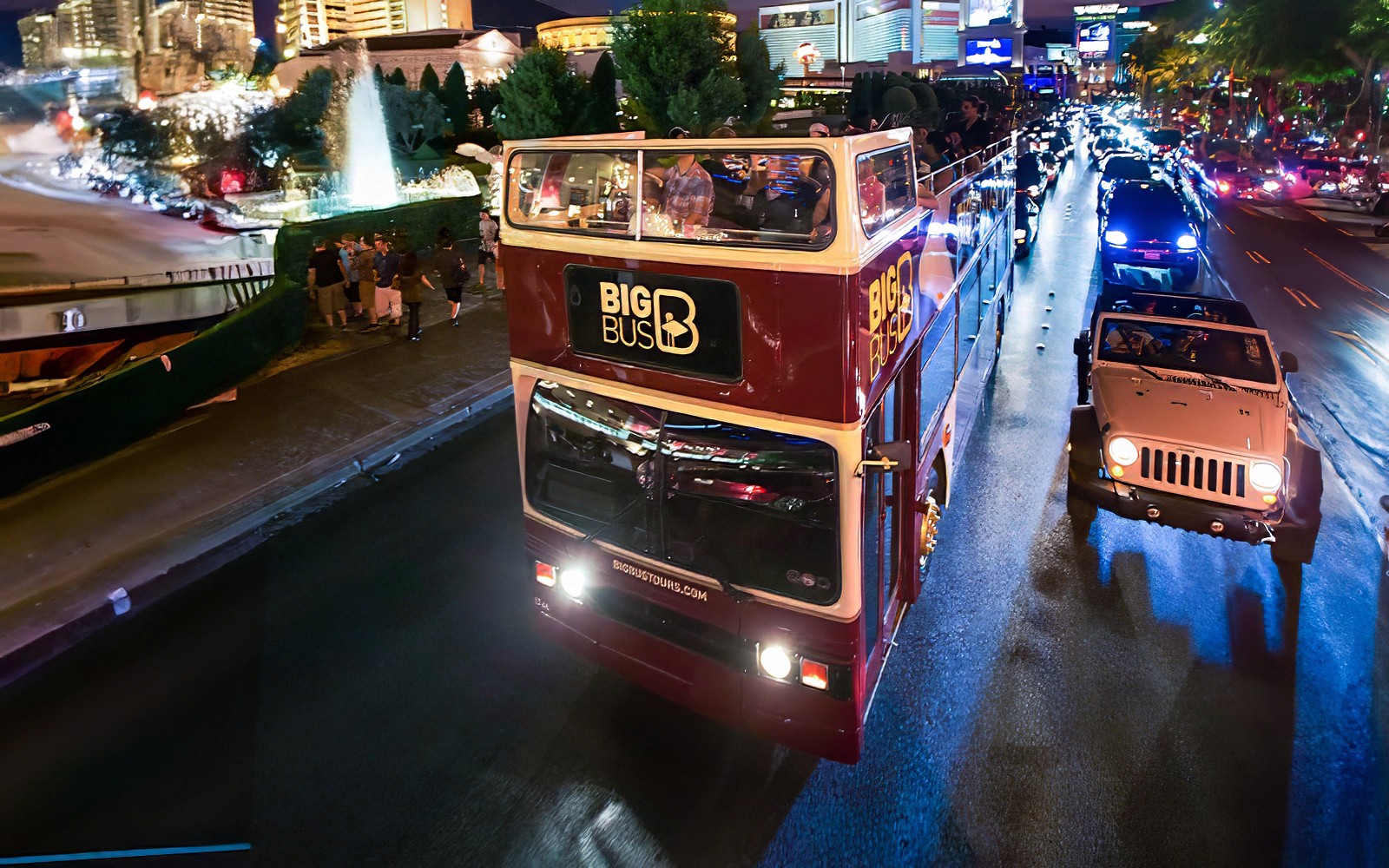 Big Bus night tour on road in Madrid with city lights in background.