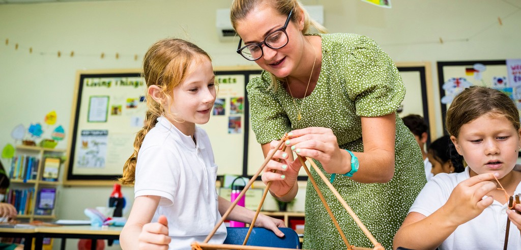 A junior school girl working with a female teacher to build a structure