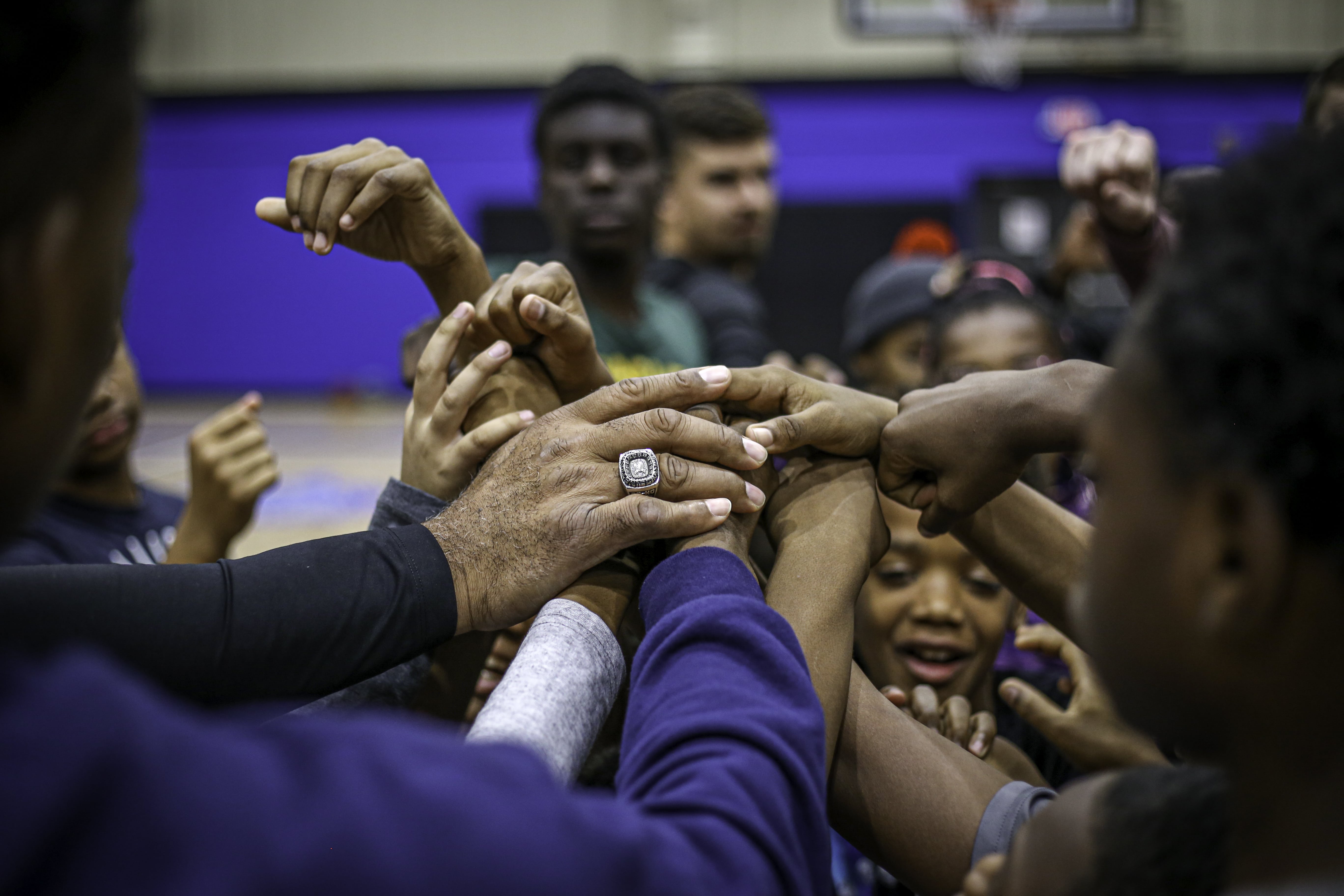 Team of young basketball players huddled in unity during training at Elevate Your Game.