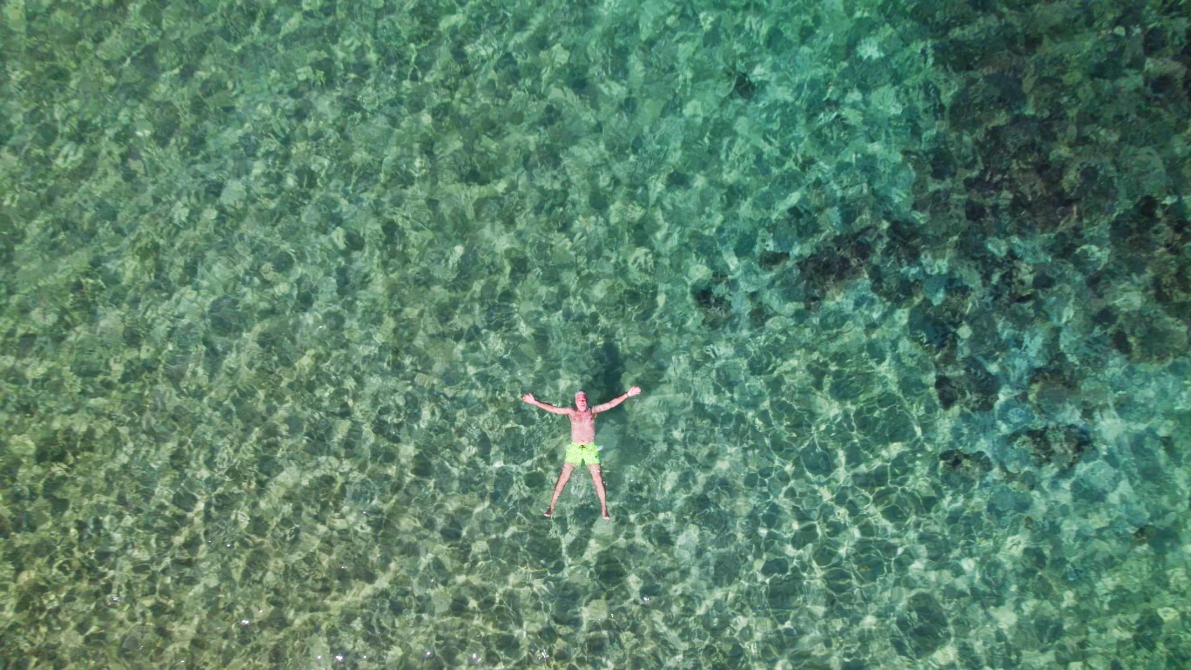 Front cover image for a short film made for TUI. The image shows a man laying in a crystal clear lagoon.