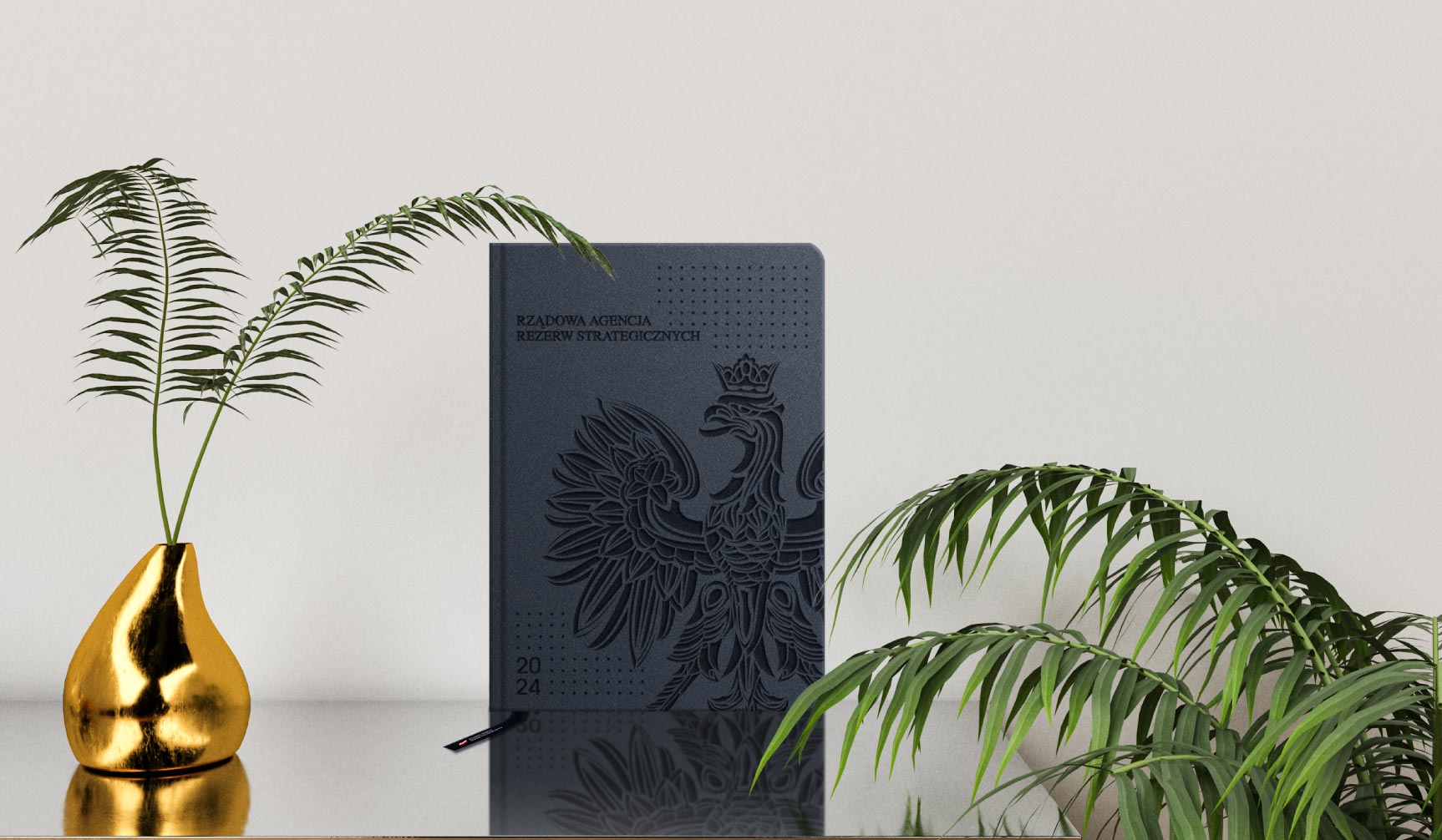 Branding gadżetów urzędowych: wizualizacja czarnego notesu z tłoczonym godłem Polski.