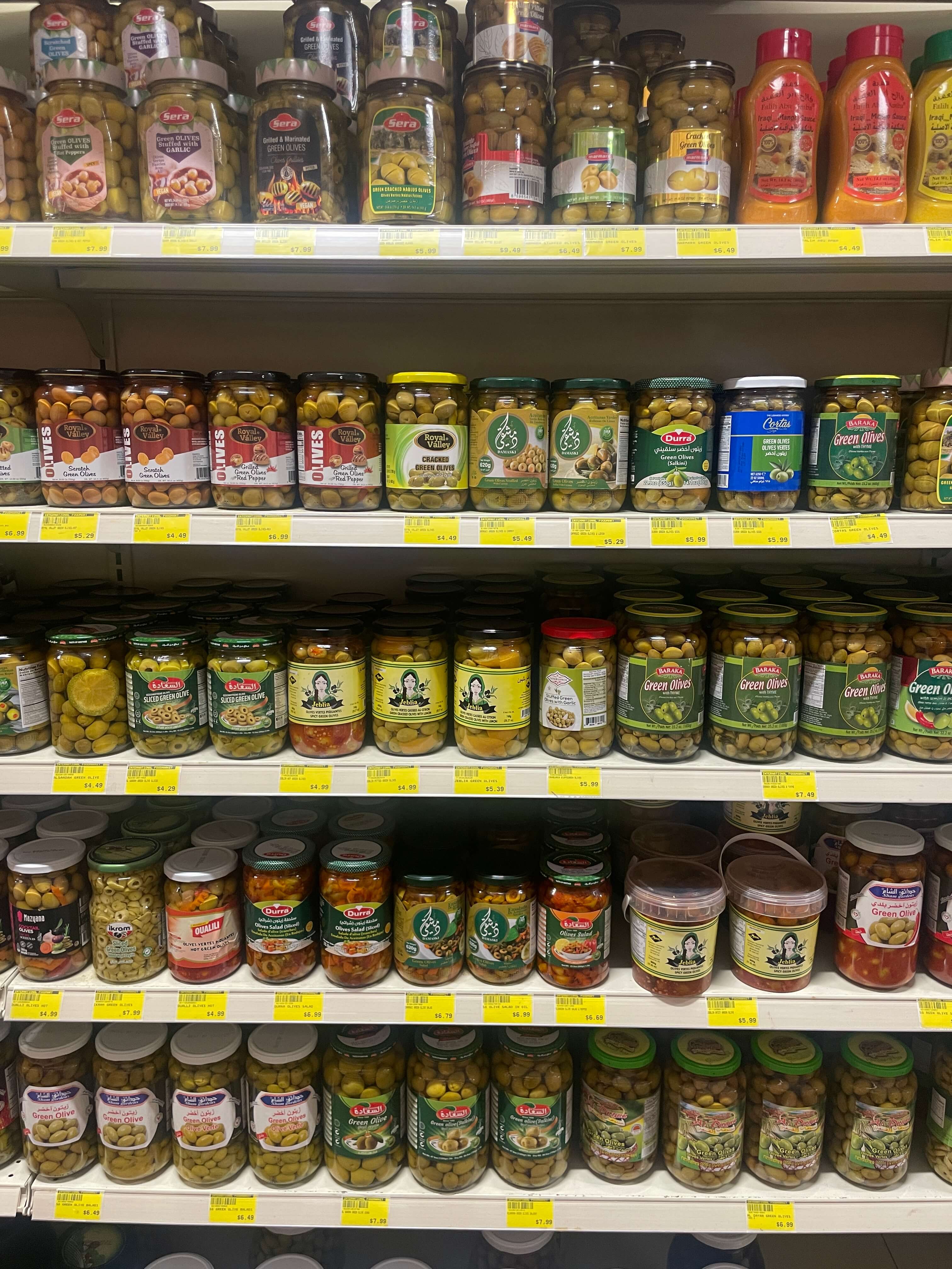 Variety of jarred olives, pickled vegetables, and Middle Eastern condiments at International Food Market Orlando.