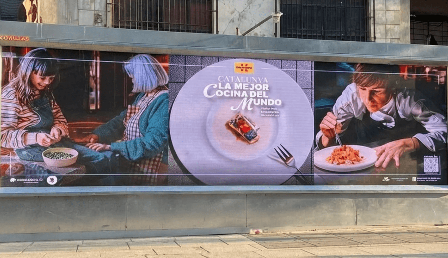 a man walking down a street past a large poster