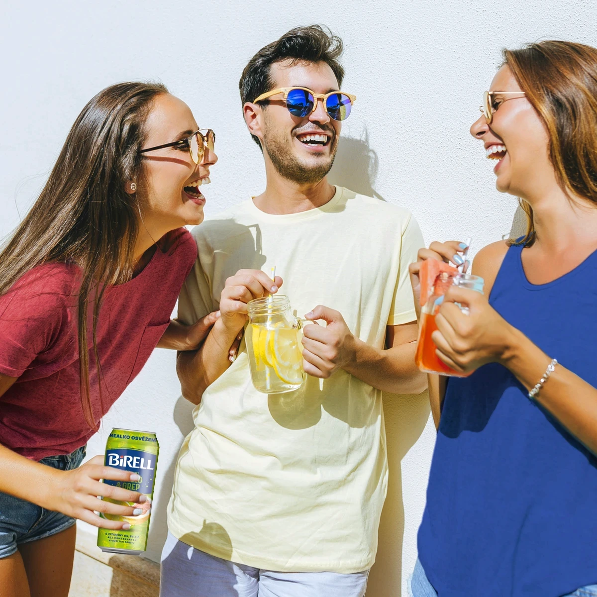 Young man and two women laughing and drinking Birell