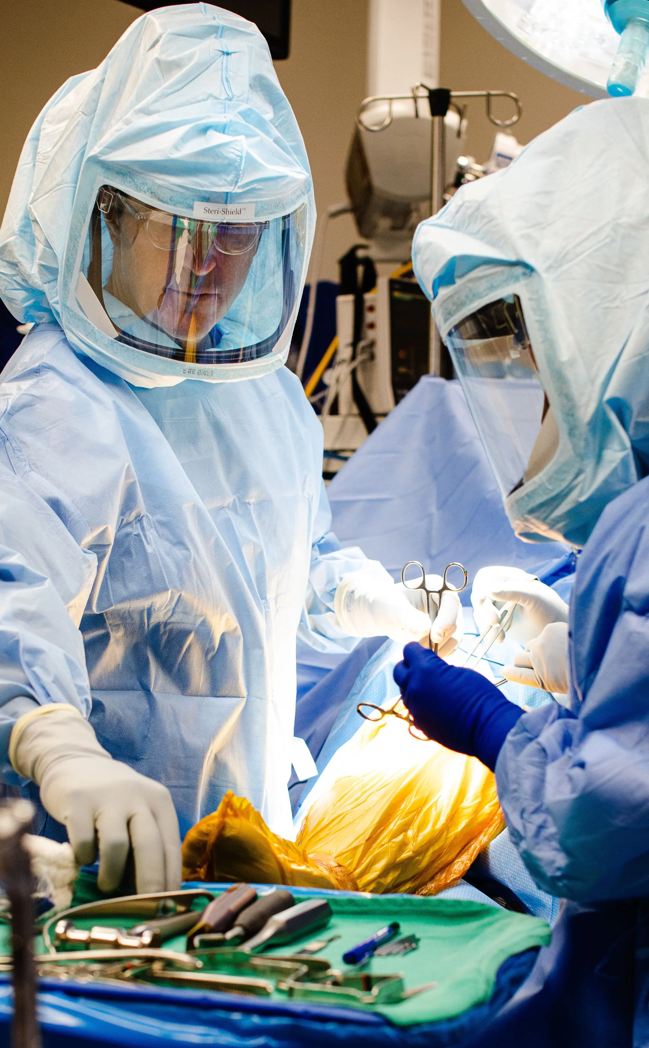 Orthopedic surgeons in full PPE performing joint procedure in sterile environment