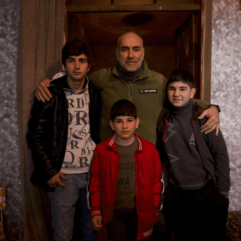 A man with three children in the doorway of their home