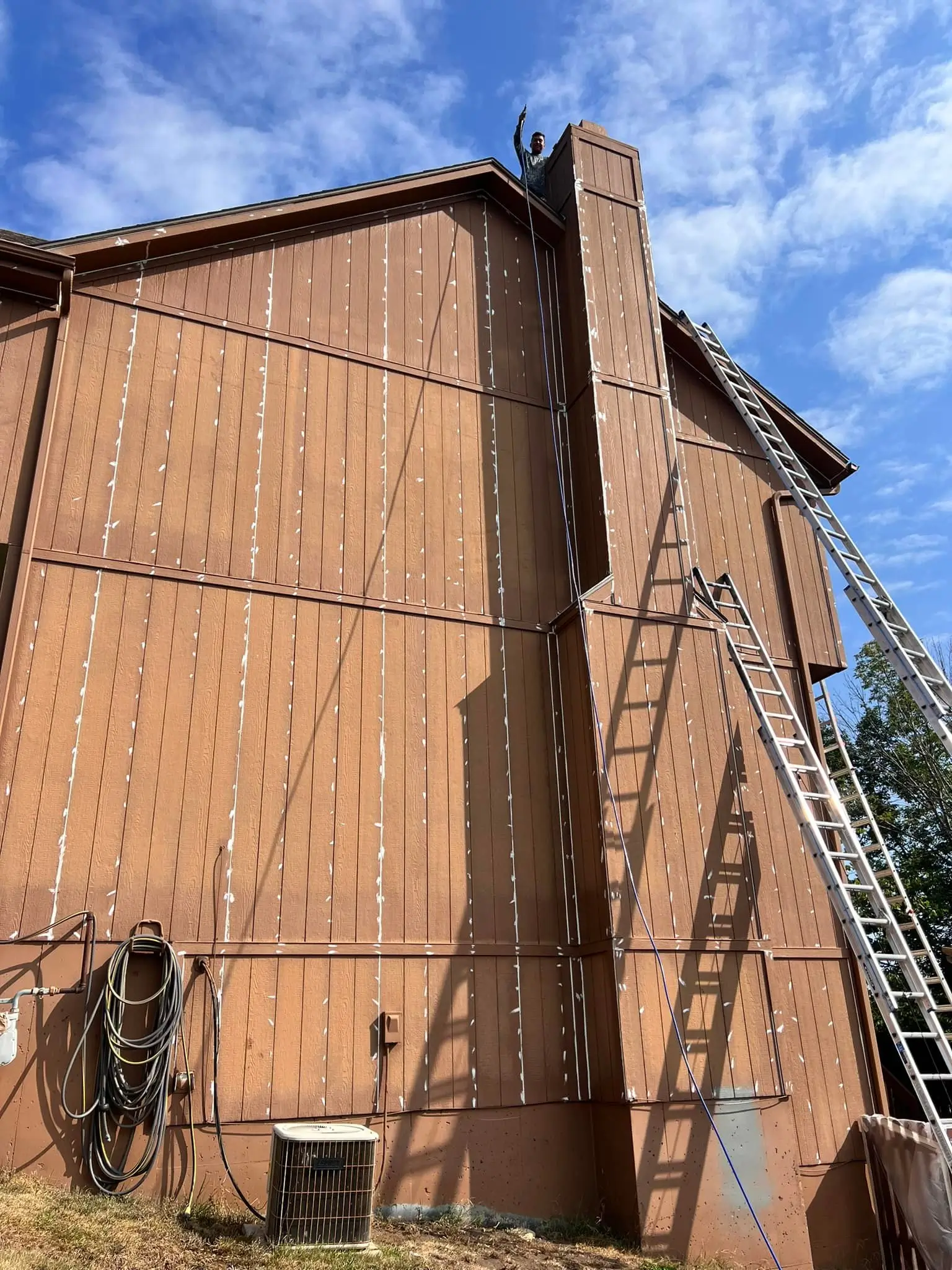An image of a brown house prepared for wood rot repairs and painting.