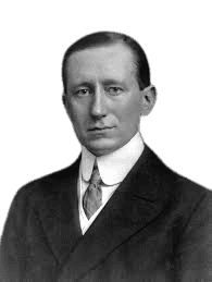 Black and white portrait of Guglielmo Marconi, the Italian inventor and electrical engineer known for pioneering long-distance radio transmission and wireless telegraphy. He is shown wearing a formal suit, white shirt, and tie, with a serious expression, highlighting his significance in the development of modern communication technology.