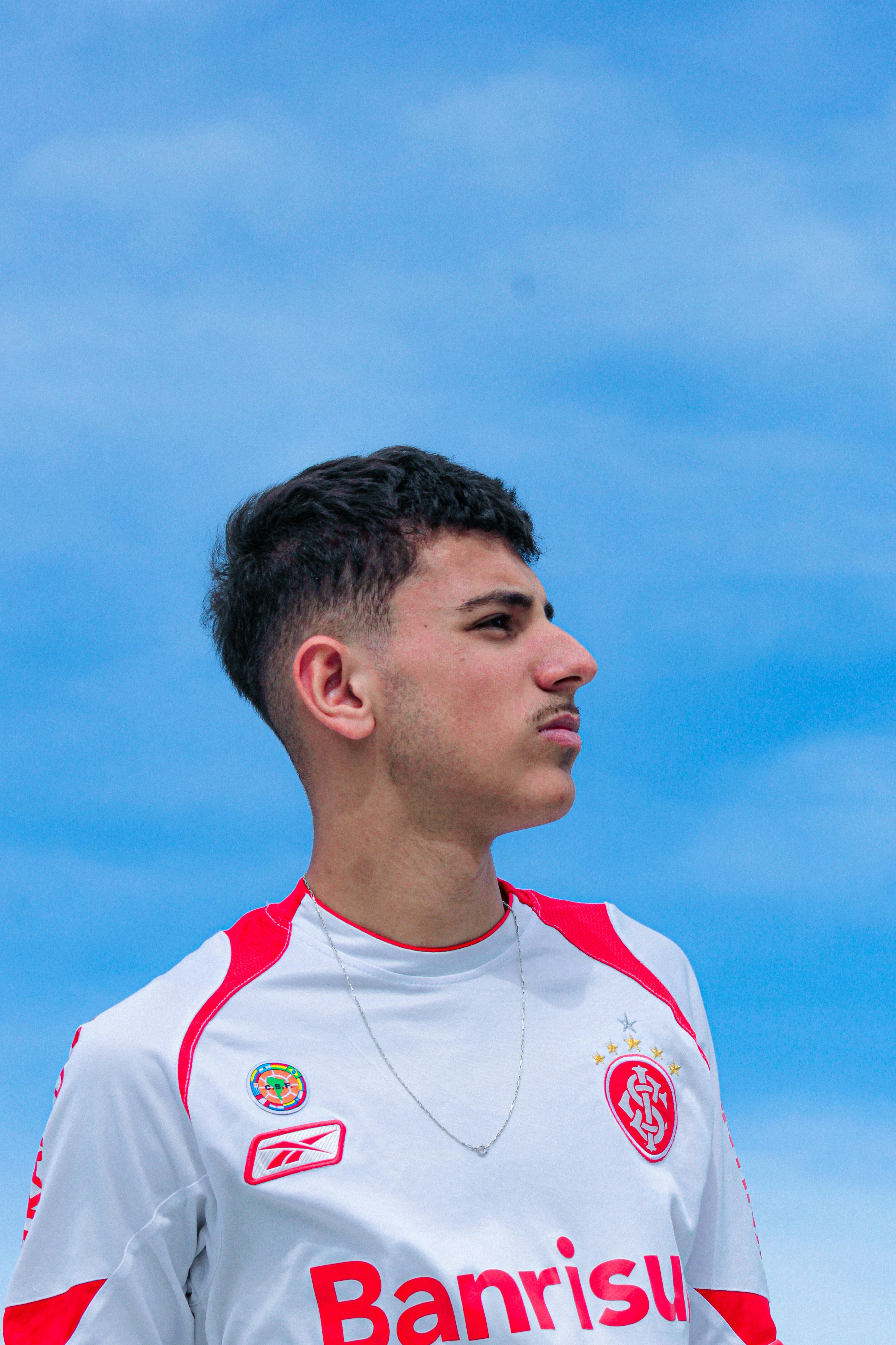 Young man in a white jersey against blue sky