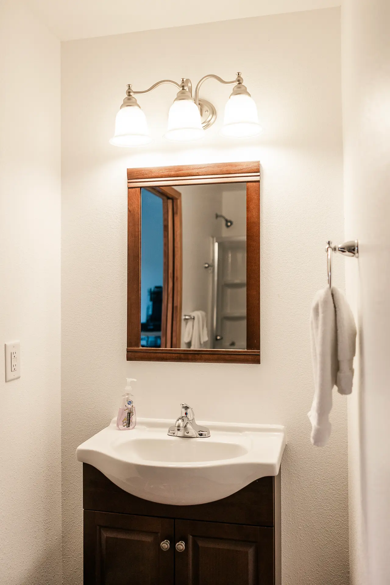 Bathroom vanity with mirror, lighting, and fresh towels.