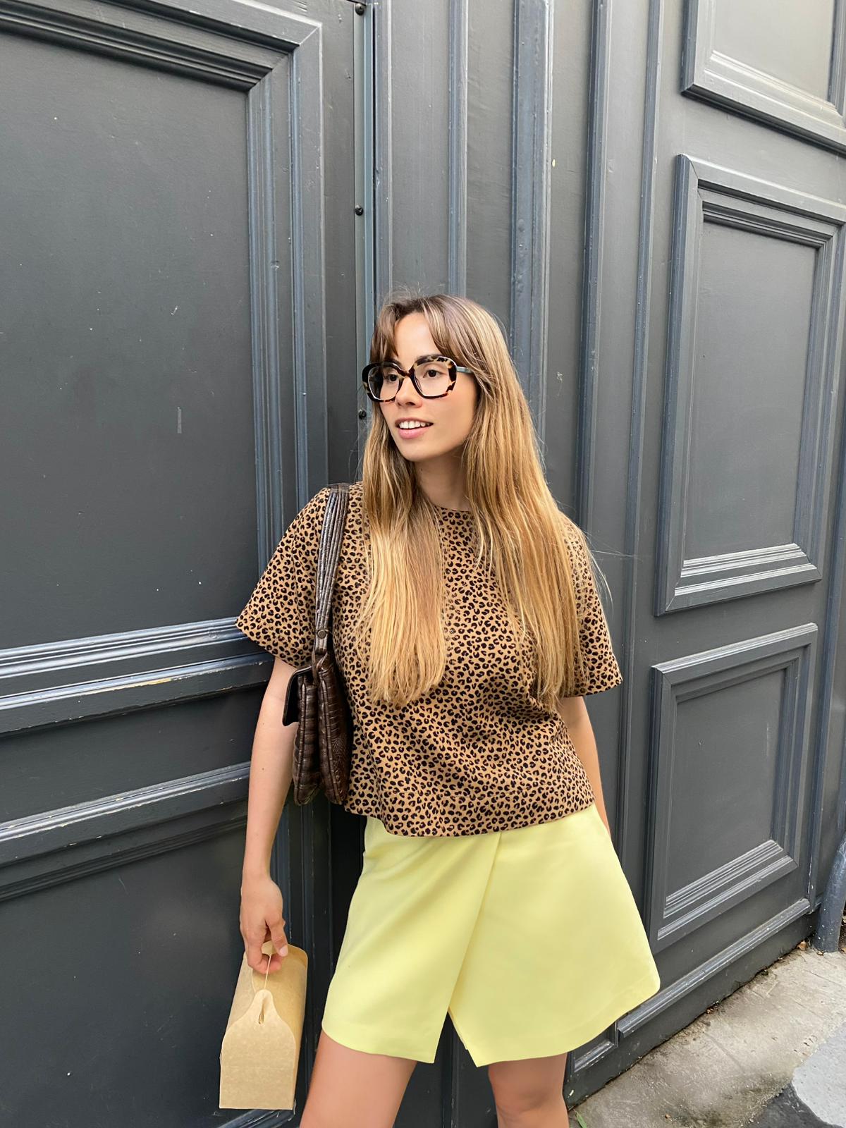 Woman working on a laptop computer at a table in a bright room.