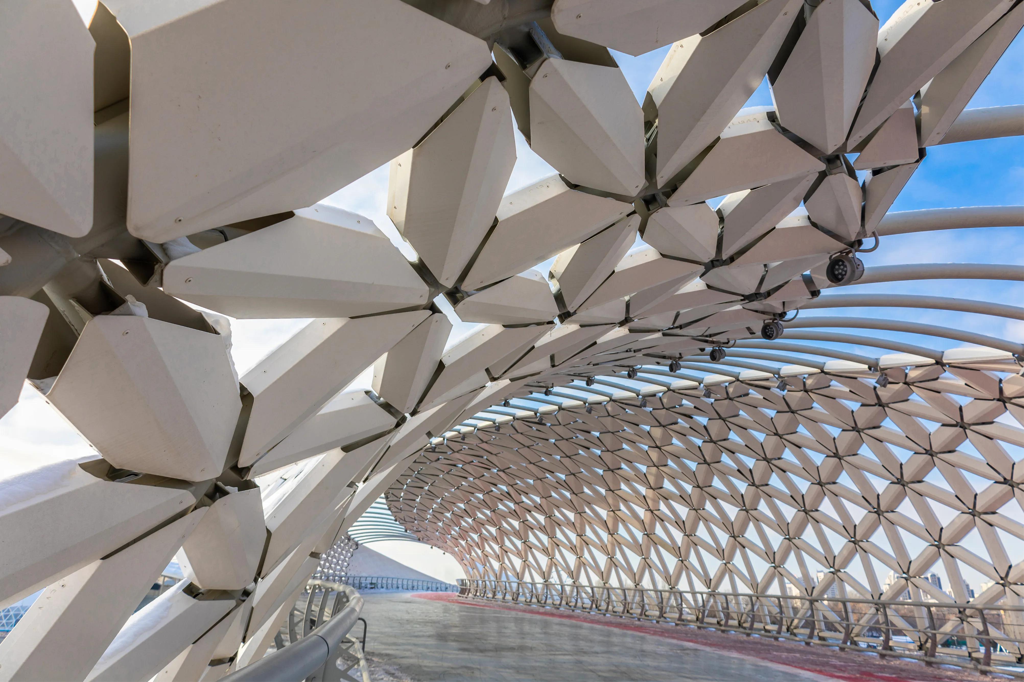 Intricate parametric bridge design featuring a white geometric lattice shell and a curved pedestrian walkway