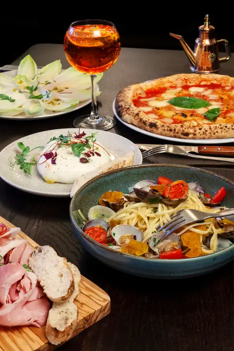 Ensemble de plats maison : burrata crémeuse des pouilles, spaghetti aux légumes méditerranéen, et l'incontournable pizza margherita.