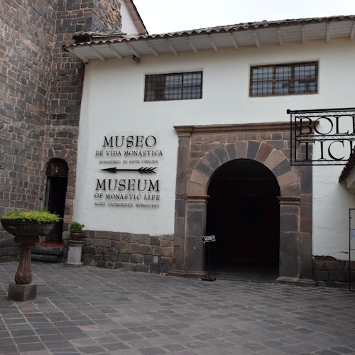 進入修道生活博物館的石拱門和庭院，並有英文和西班牙文的標誌。