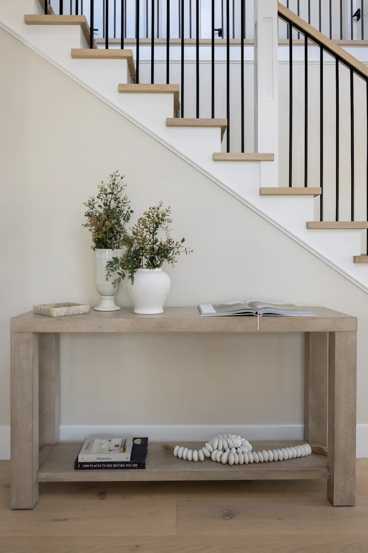 Portrait of console table against the staircase in the Irvine Contemporary Coastal Remodel. Photo by Molly Rose Photography.