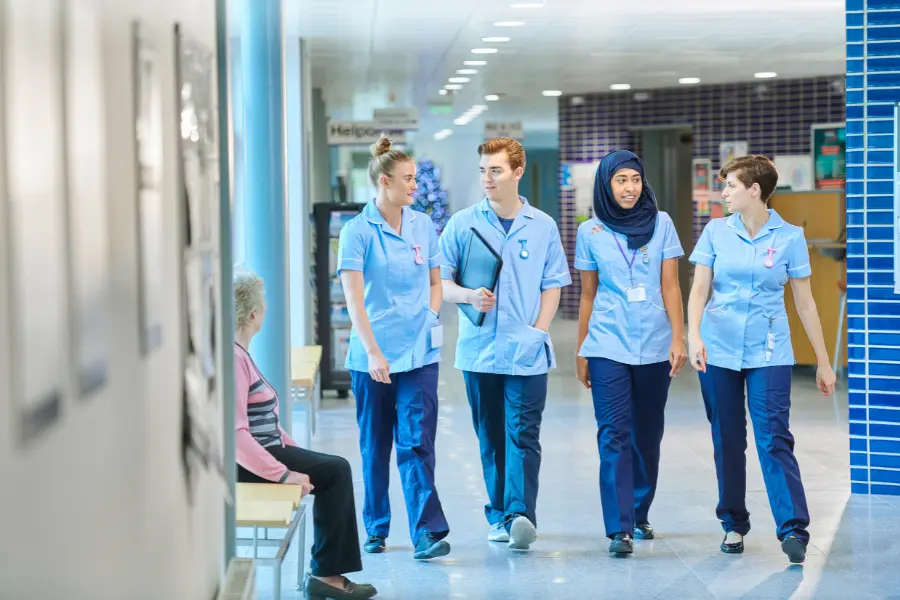 Top AI medical coders represented by a diverse group of healthcare professionals walking through a hospital corridor.